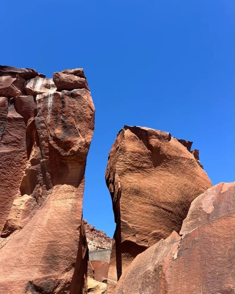 Tall weathered rock walls of a desert gorge closing in overhead against the sky